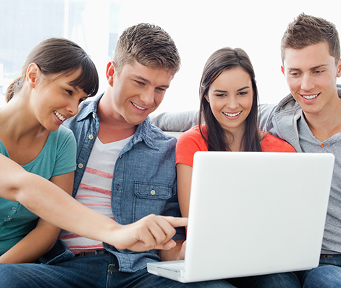 Grupo de j&oacute;venes viendo laptop juntos
